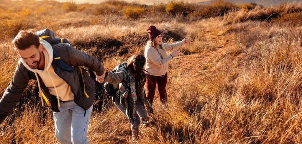 Friends hiking up a sunny grassy hill