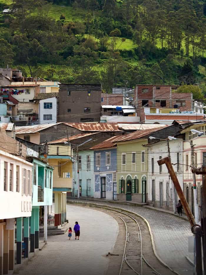 Colorful town street with railway and green hills