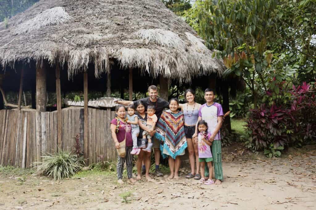 Group smiling outside traditional thatched hut