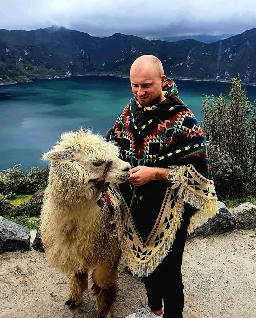 Man petting llama near mountain lake