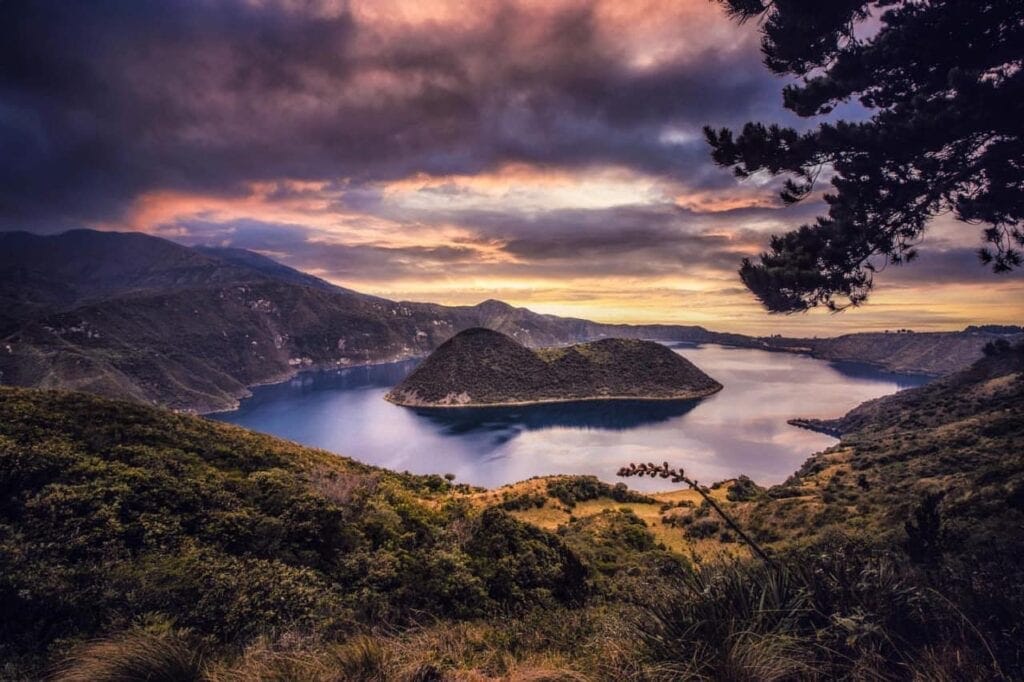 Mountain lake with island under colorful sunset sky