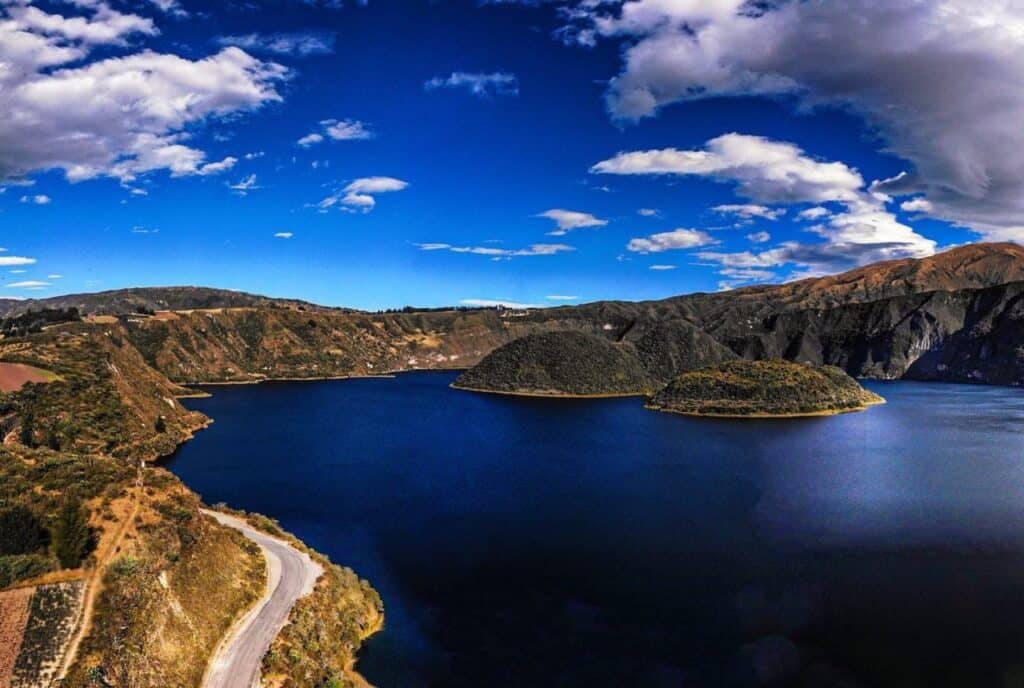Blue lake surrounded by green mountains and clouds