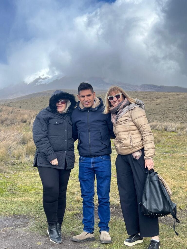 Three friends posing outdoors near a cloudy mountain.